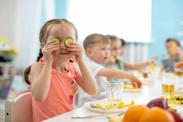 Enfants à la cantine qui mangent des légumes