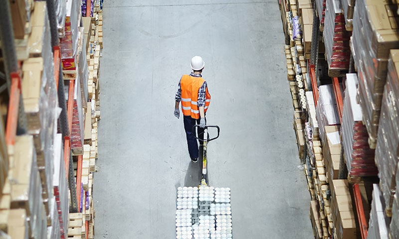 Opérateur logistique déplaçant des marchandises dans un entrepôt Opérateur logistique déplaçant des marchandises dans un entrepôt